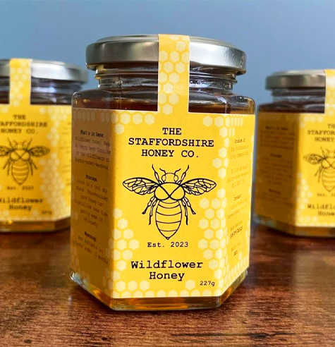 Jars of honey with custom shape labels applied to them.